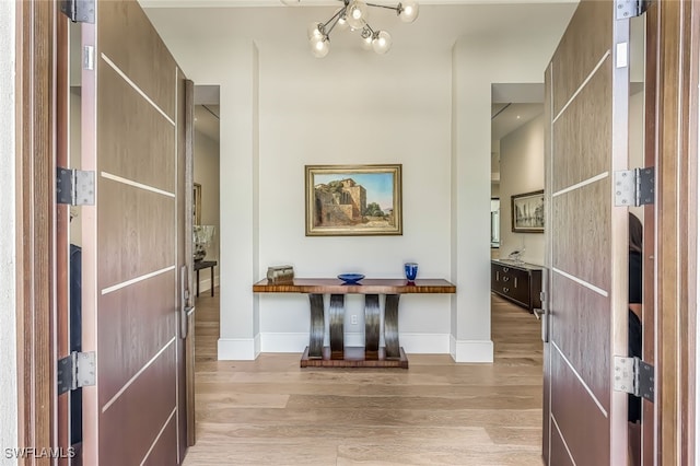 hallway with a notable chandelier and light wood-type flooring