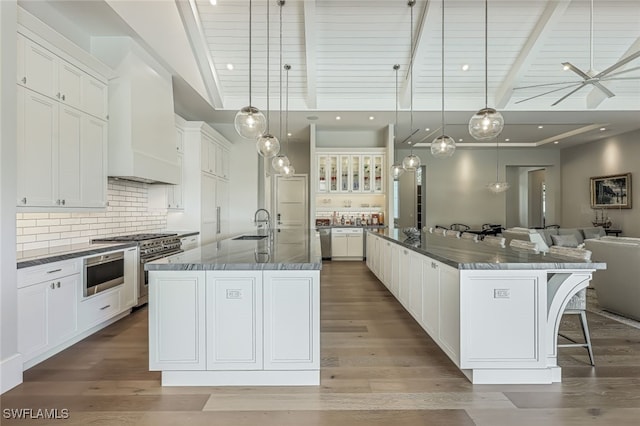 kitchen featuring decorative light fixtures, a spacious island, white cabinetry, and appliances with stainless steel finishes