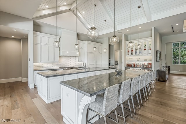 kitchen with white cabinets, a large island with sink, and pendant lighting