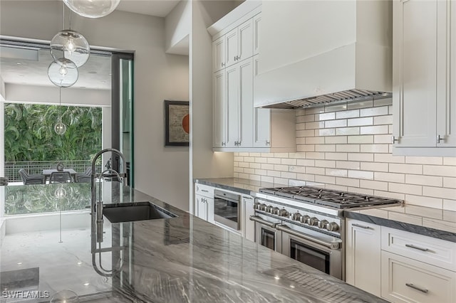 kitchen with white cabinetry, sink, tasteful backsplash, premium range hood, and double oven range