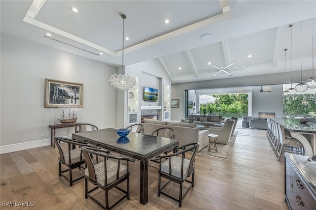 dining space featuring vaulted ceiling with beams, light hardwood / wood-style floors, and an inviting chandelier