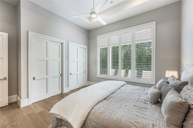 bedroom featuring multiple closets, ceiling fan, and light wood-type flooring