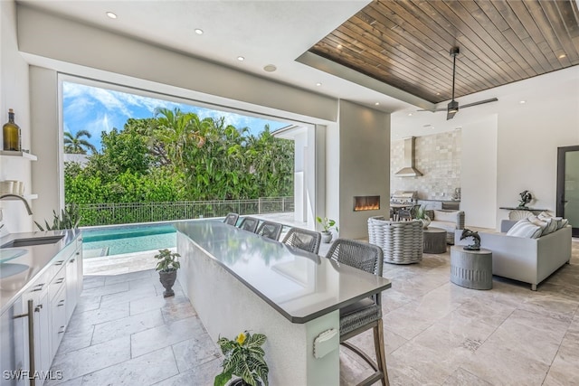 interior space featuring an outdoor hangout area, ceiling fan, sink, exterior kitchen, and a fenced in pool