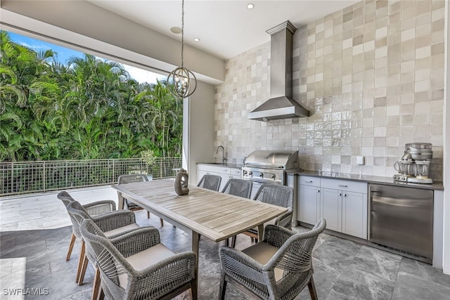 interior space with stainless steel refrigerator, sink, wall chimney range hood, backsplash, and pendant lighting