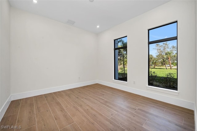 unfurnished room with recessed lighting, wood finished floors, and baseboards