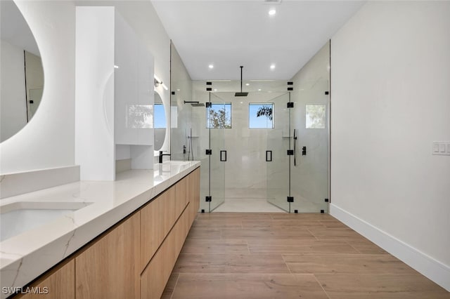 bathroom featuring double vanity, a stall shower, wood finished floors, a sink, and recessed lighting