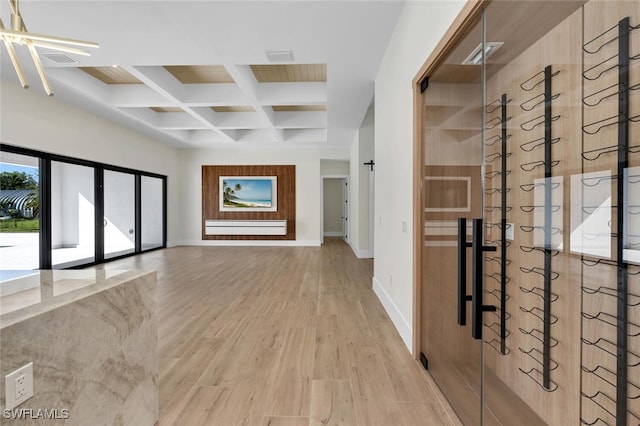 interior space with light wood-type flooring, baseboards, coffered ceiling, and beam ceiling