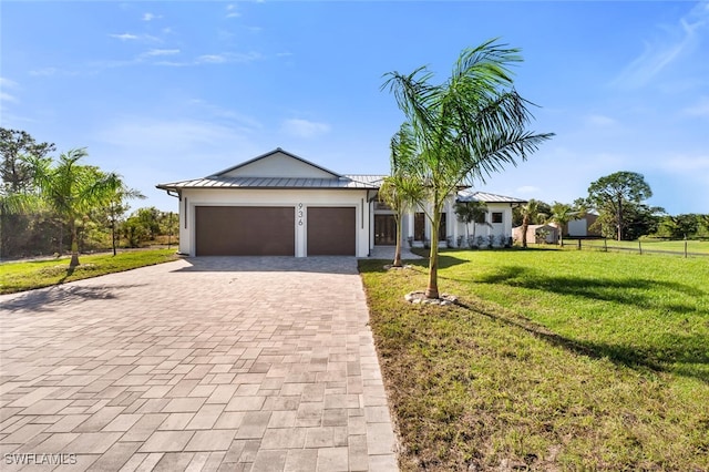 ranch-style home featuring metal roof, an attached garage, a standing seam roof, decorative driveway, and a front lawn