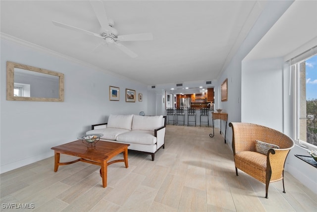 living room with ceiling fan, ornamental molding, and light hardwood / wood-style flooring