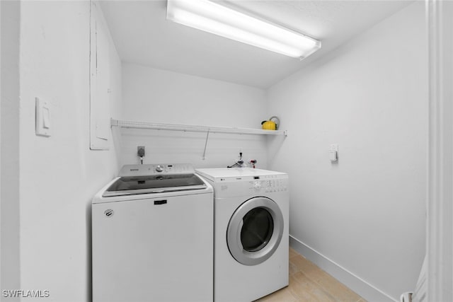 laundry room with separate washer and dryer and light hardwood / wood-style flooring