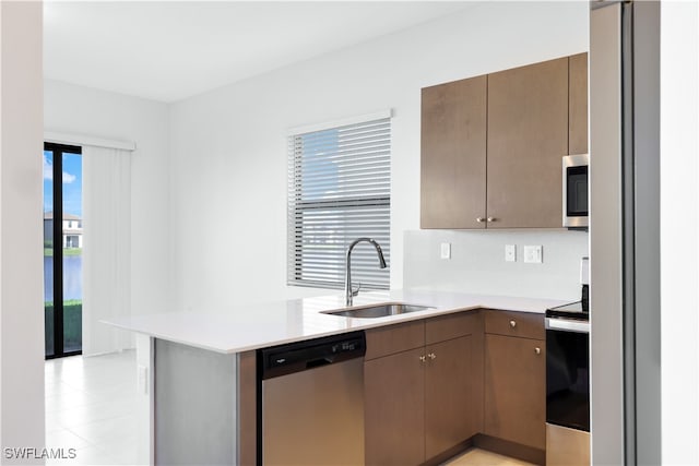 kitchen with backsplash, sink, kitchen peninsula, and stainless steel appliances