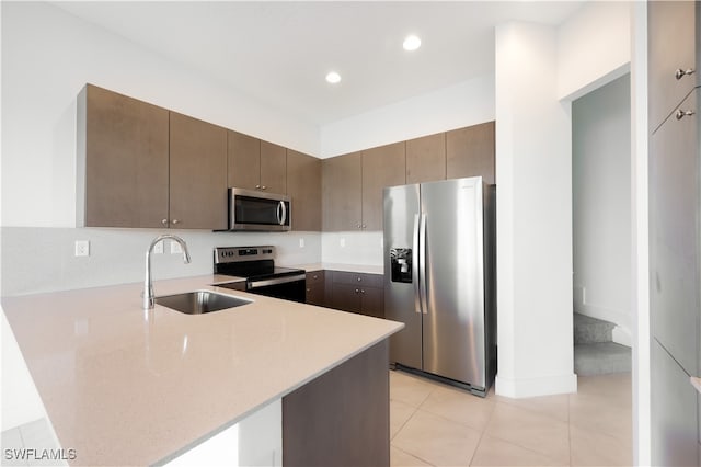 kitchen featuring light tile patterned flooring, kitchen peninsula, sink, and appliances with stainless steel finishes