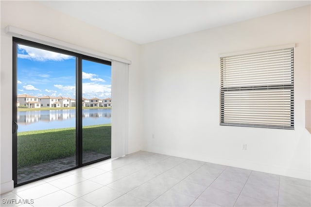 empty room with light tile patterned floors and a water view