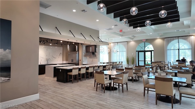 dining space featuring beam ceiling, light wood-type flooring, and sink