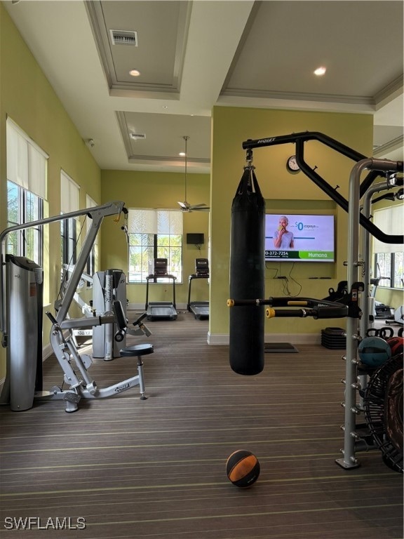 workout area featuring dark colored carpet, a tray ceiling, and crown molding