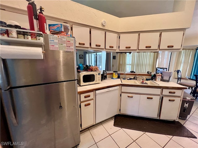 kitchen featuring kitchen peninsula, white appliances, sink, white cabinetry, and light tile patterned flooring