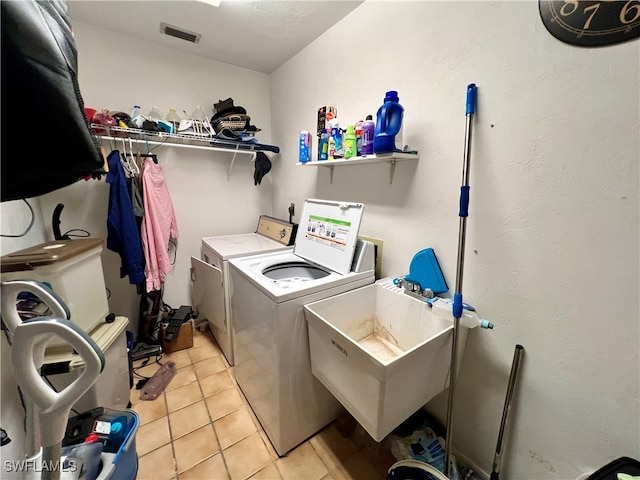 clothes washing area featuring sink, washer and clothes dryer, and light tile patterned flooring