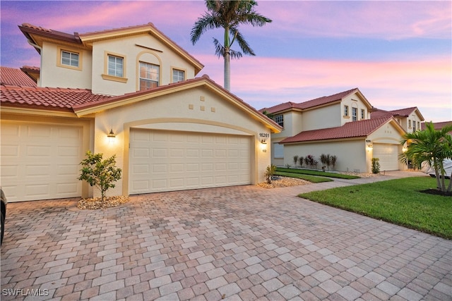 mediterranean / spanish house featuring a yard and a garage