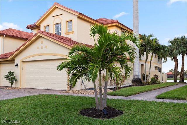 mediterranean / spanish house with a garage and a front lawn