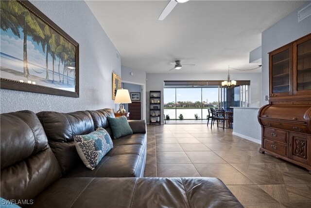 living room with ceiling fan with notable chandelier and a water view