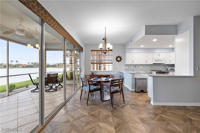 dining room featuring plenty of natural light, a water view, a notable chandelier, and sink