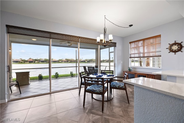 dining area featuring parquet floors, a water view, a healthy amount of sunlight, and a notable chandelier