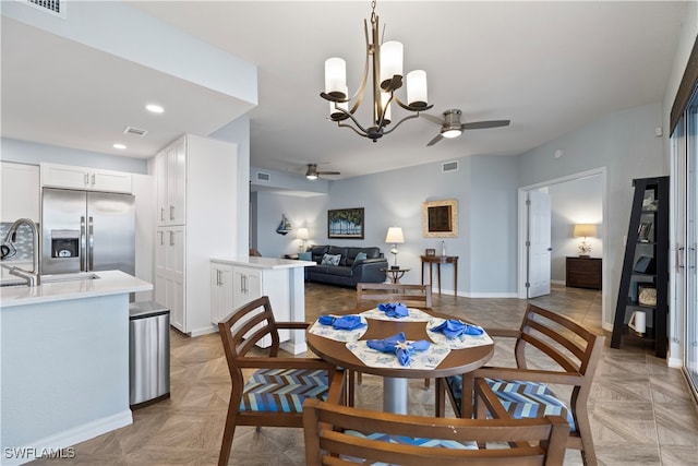 dining area featuring ceiling fan with notable chandelier, sink, and light parquet flooring