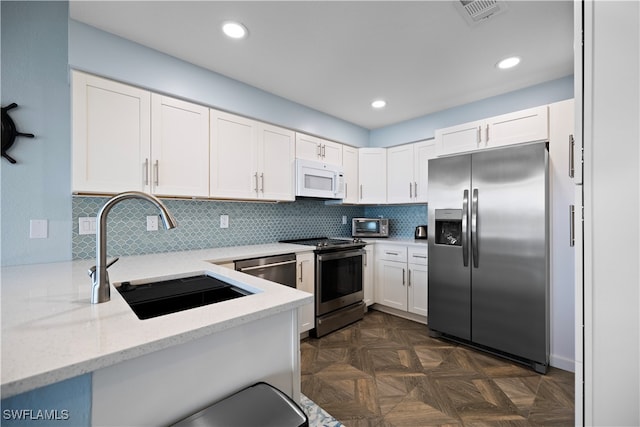 kitchen with white cabinetry, light stone countertops, stainless steel appliances, tasteful backsplash, and kitchen peninsula