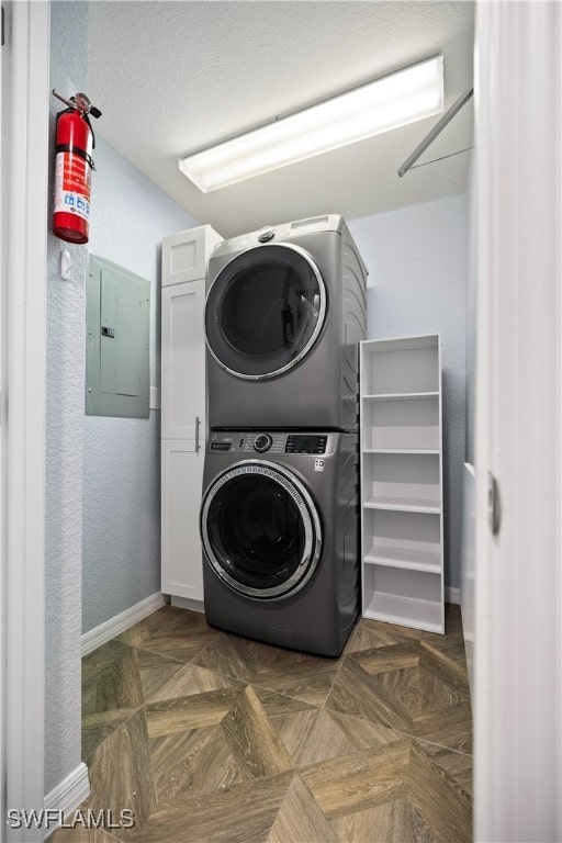 laundry room featuring stacked washer / dryer, electric panel, dark parquet floors, and cabinets