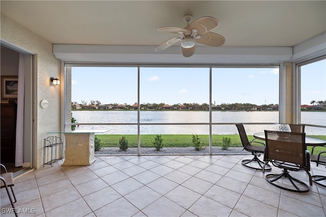 sunroom with ceiling fan and a water view