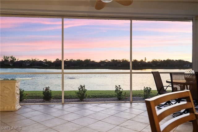 unfurnished sunroom featuring ceiling fan and a water view