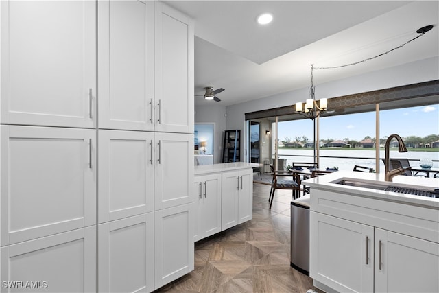 kitchen featuring light parquet floors, ceiling fan with notable chandelier, white cabinetry, and sink