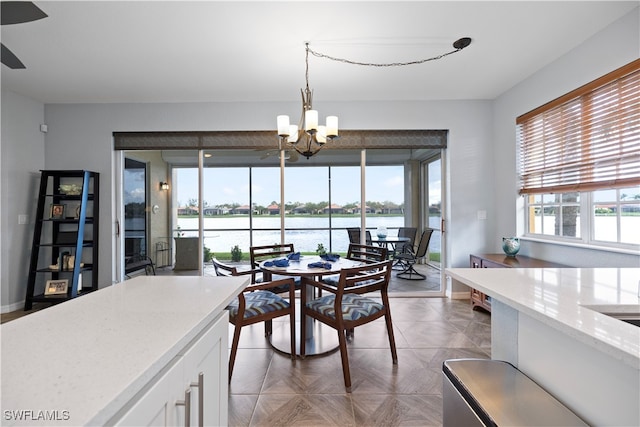 dining area featuring a water view and a notable chandelier