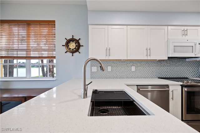 kitchen featuring decorative backsplash, light stone counters, white cabinets, and stainless steel appliances