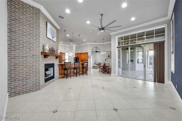 unfurnished living room featuring ceiling fan, ornamental molding, light tile patterned floors, and a brick fireplace