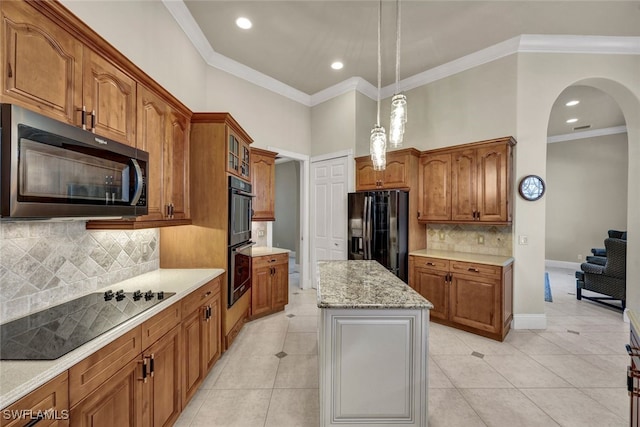 kitchen featuring black appliances, ornamental molding, a kitchen island, light tile patterned flooring, and brown cabinetry