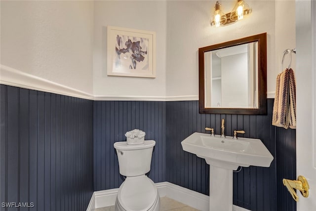 bathroom with tile patterned floors, toilet, and wainscoting