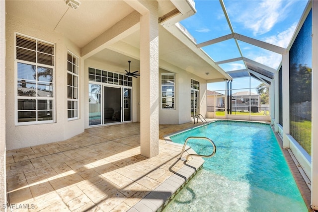 outdoor pool with glass enclosure, ceiling fan, and a patio area