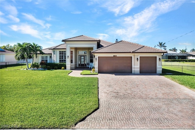 prairie-style home with a tiled roof, a front yard, decorative driveway, and a garage