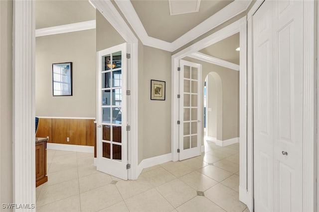 hallway featuring light tile patterned flooring, crown molding, wooden walls, and french doors