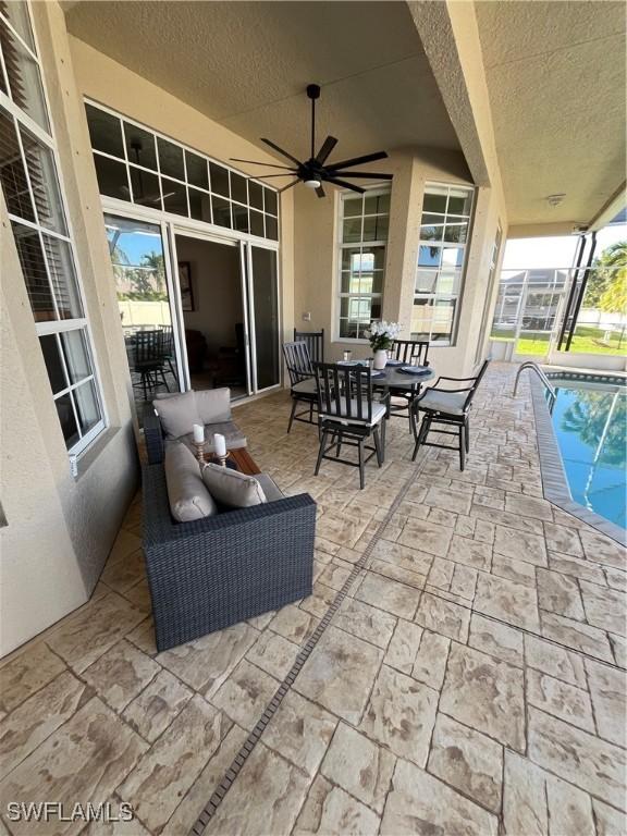 view of patio / terrace featuring a lanai, an outdoor pool, outdoor dining area, and ceiling fan