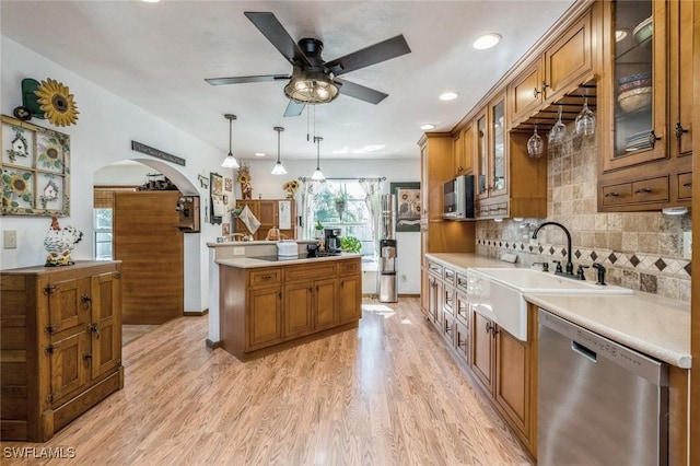 kitchen with pendant lighting, tasteful backsplash, sink, stainless steel appliances, and light wood-type flooring