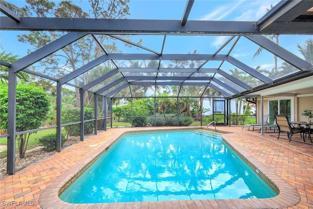 view of pool with glass enclosure and a patio area