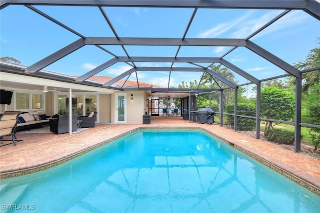 view of swimming pool featuring an outdoor living space, glass enclosure, grilling area, ceiling fan, and a patio area