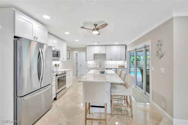 kitchen featuring stainless steel appliances, a kitchen island, light stone counters, a kitchen bar, and white cabinets