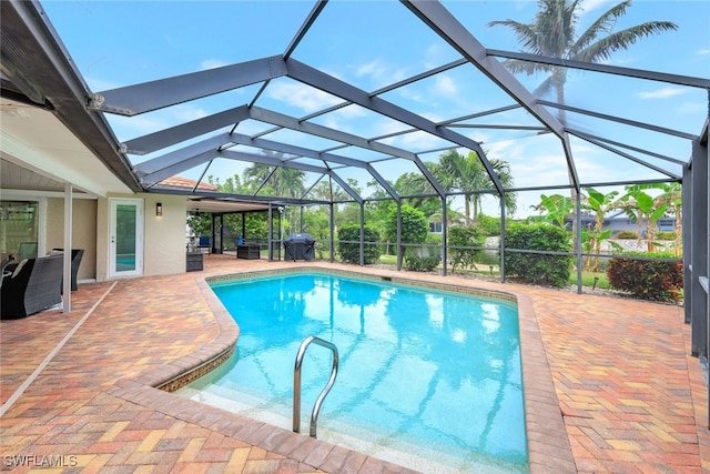 view of pool with glass enclosure and a patio