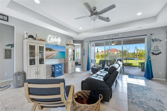 tiled living room featuring ceiling fan and a tray ceiling