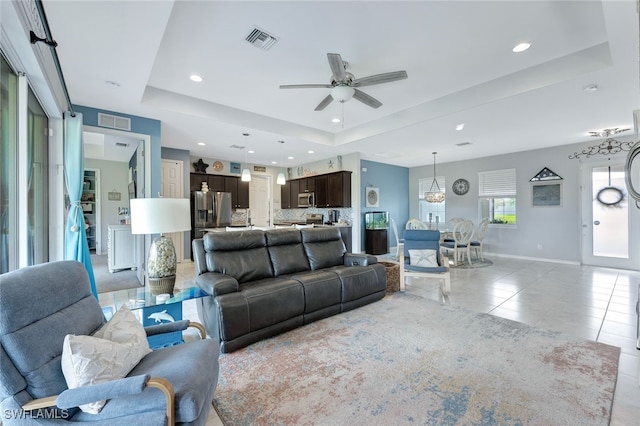 tiled living room featuring a raised ceiling and ceiling fan