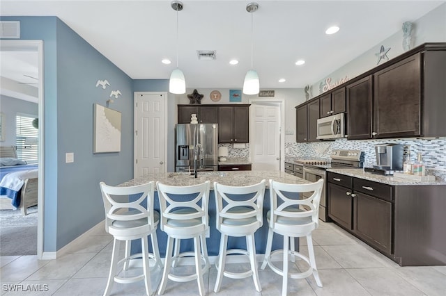 kitchen featuring pendant lighting, sink, a kitchen island with sink, stainless steel appliances, and dark brown cabinets