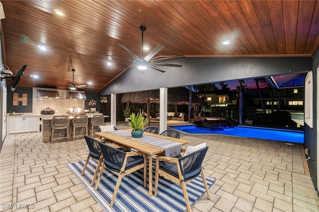 view of patio with an outdoor kitchen, ceiling fan, and a bar